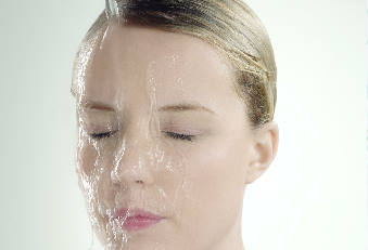 Frau mit Wasserstrahl auf der Stirn