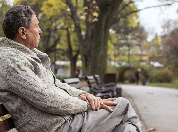 Mann sitzt allein auf einer Parkbank