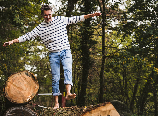Mann balanciert über einen Baumstamm