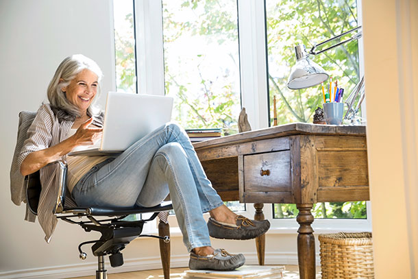 Eine Frau sitzt lachend vor einem Laptop. 