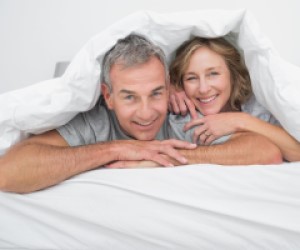 Ein reifes Paar geniesst die Zeit im Bett.