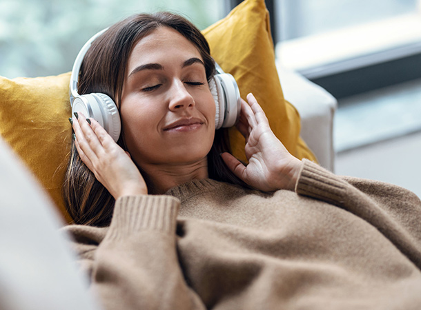 NSDR lässt sich einfach in den Alltag integrieren (Foto: Frau-Entspannung-123RF/nenetus) Frau mit Kopfhörern auf dem Sofa