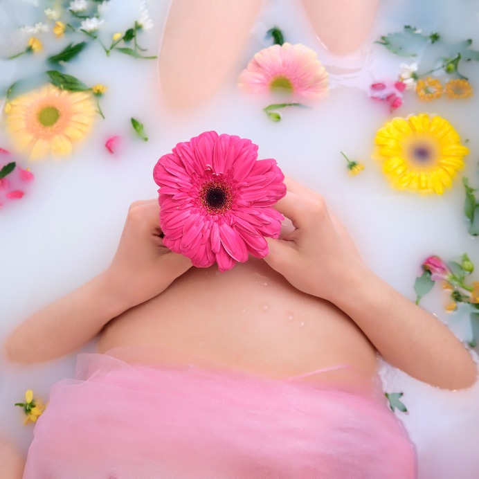 Schwangere in der Badewanne mit Blüten