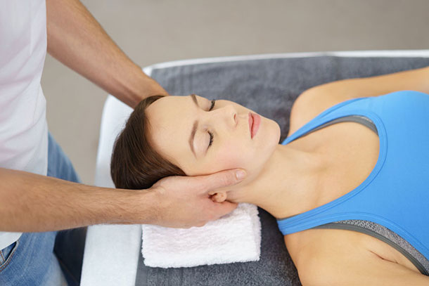 Ein Therapeut behandelt die Nackenbeschwerden einer Frau. 