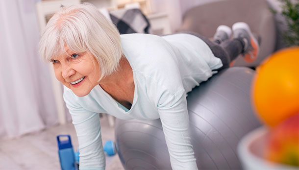 Eine reife Frau trainiert mit dem Gymnastikball.