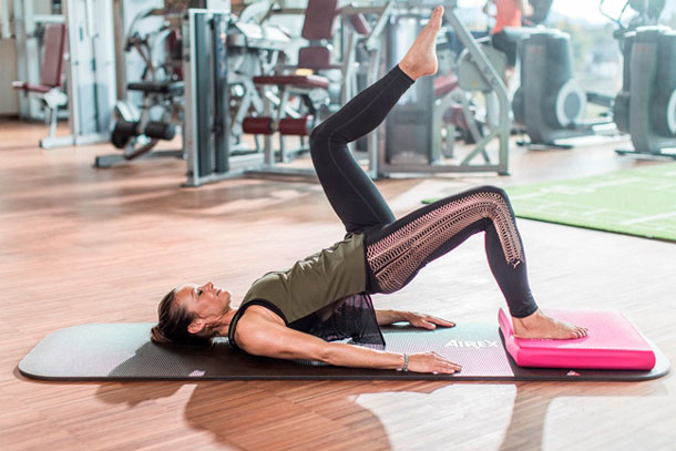 Eine Frau trainiert mit dem Airex Balancepad im Fitness-Center