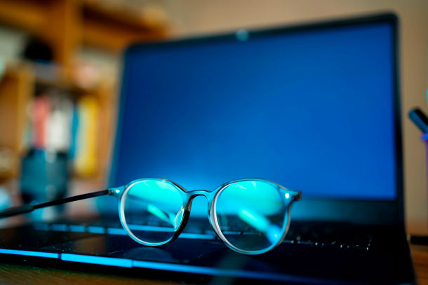 Eine Brille mit Blaufilter liegt auf einem aufgeklapptem Laptop.