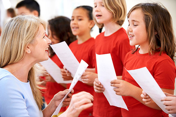 Eine Gruppe Kinder singt begeistert unter Anleitung der Chorleiterin.