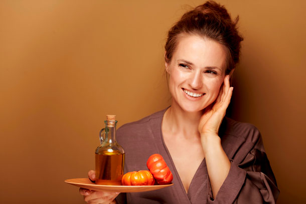 Une femme tient une tablette avec une huile de massage dans sa main.