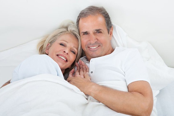 Ein glückliches Paar liegt gemütlich im Bett.